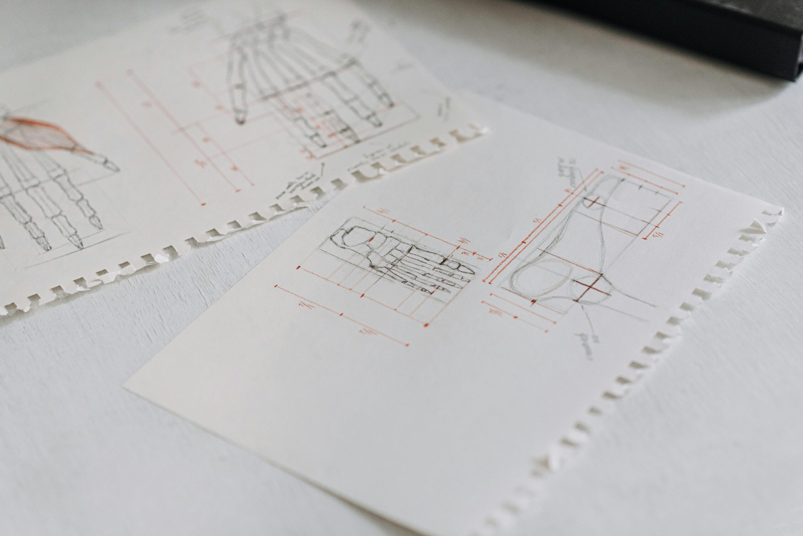 Close-up of detailed technical drawings on neatly arranged white paper sheets, highlighting design concepts.